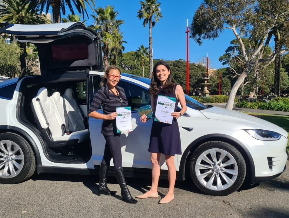 Amanda Choy & Pia Peterson standing in front of Model X with Evoke's awards.
